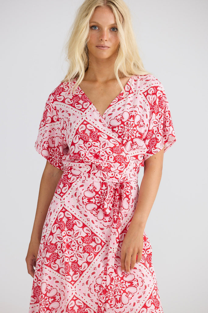 Woman wearing a red and white patterned dress on a plain background
