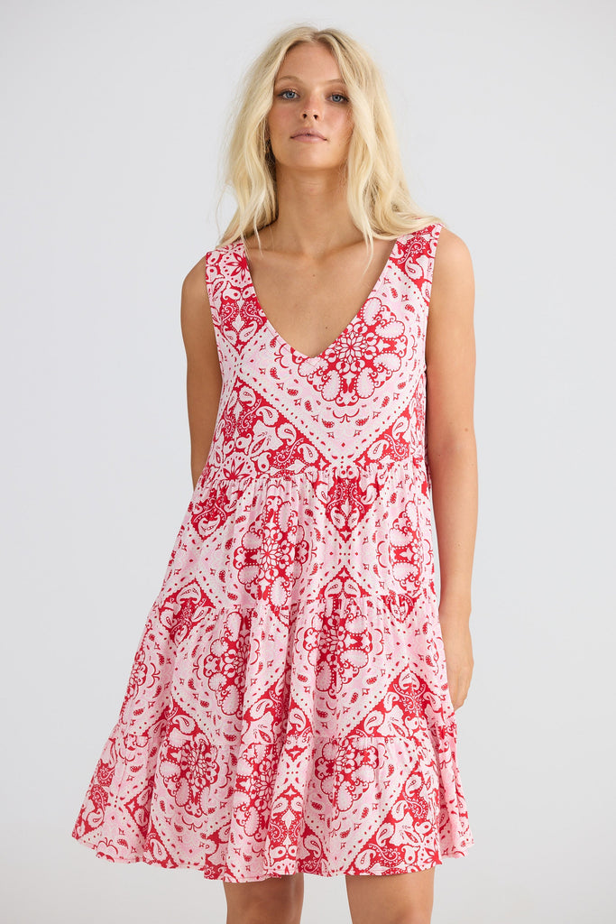 Woman wearing a red and white patterned dress on a plain background