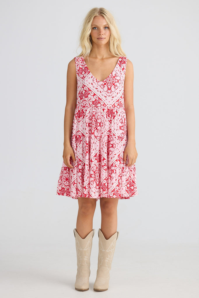 Woman wearing a red floral dress with beige boots on a white background