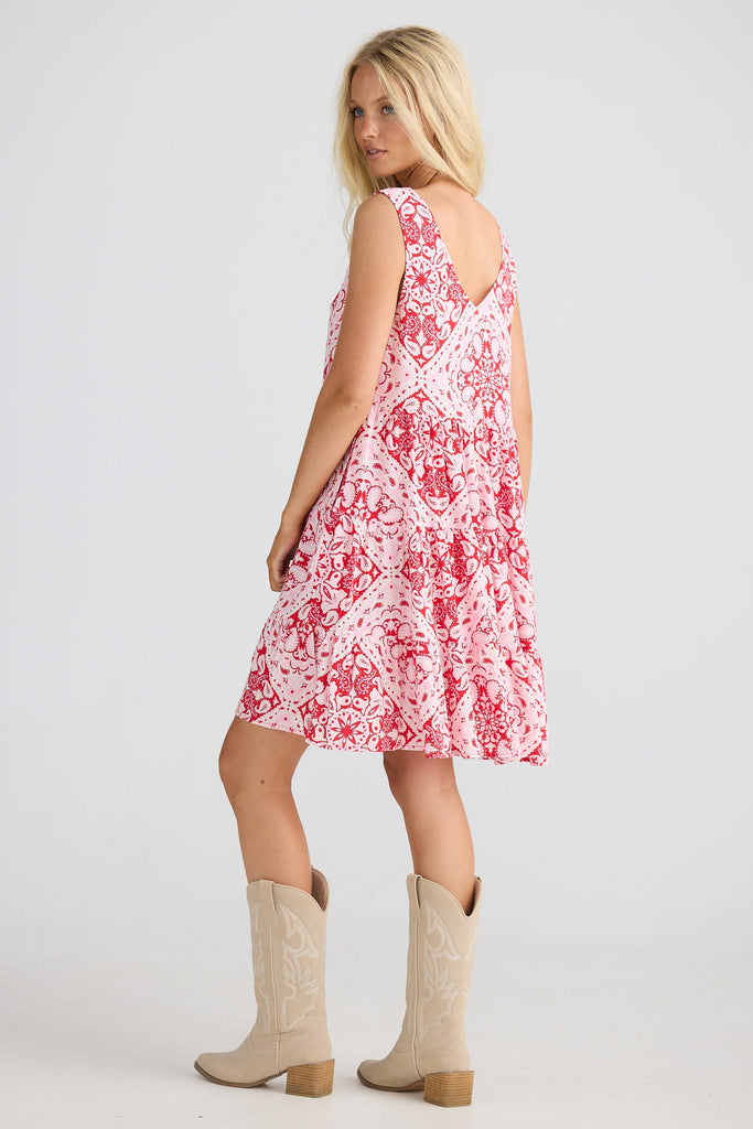 Woman wearing a red patterned dress and beige boots on a white background