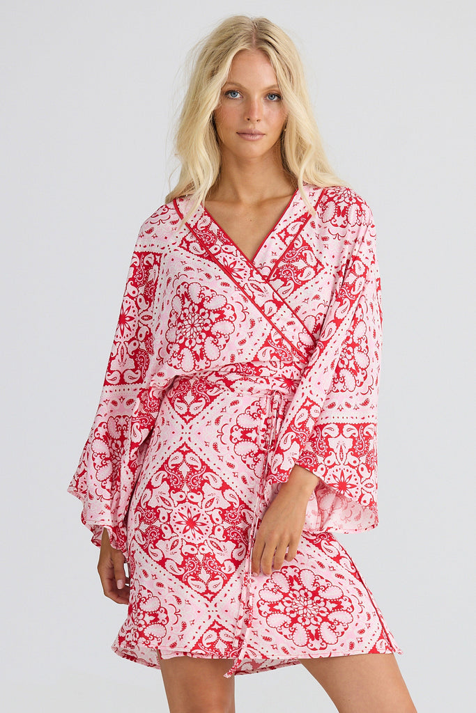 Woman wearing a red and white patterned dress on a light gray background