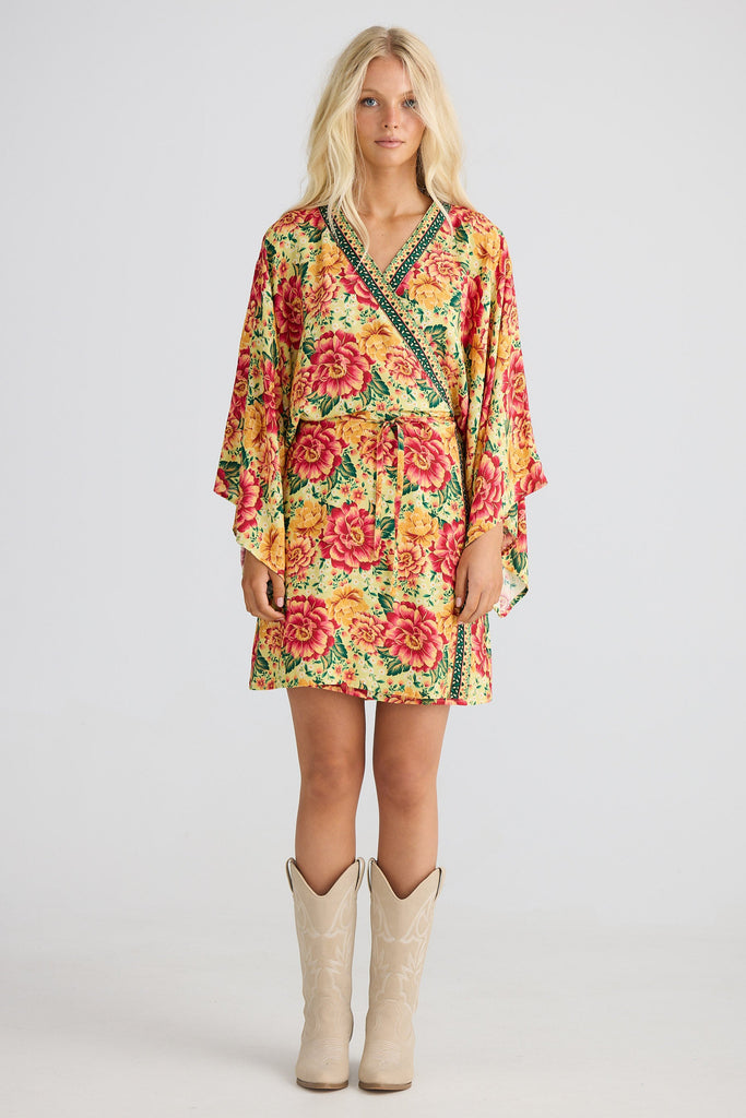 Woman wearing a colorful floral dress with beige boots on a white background