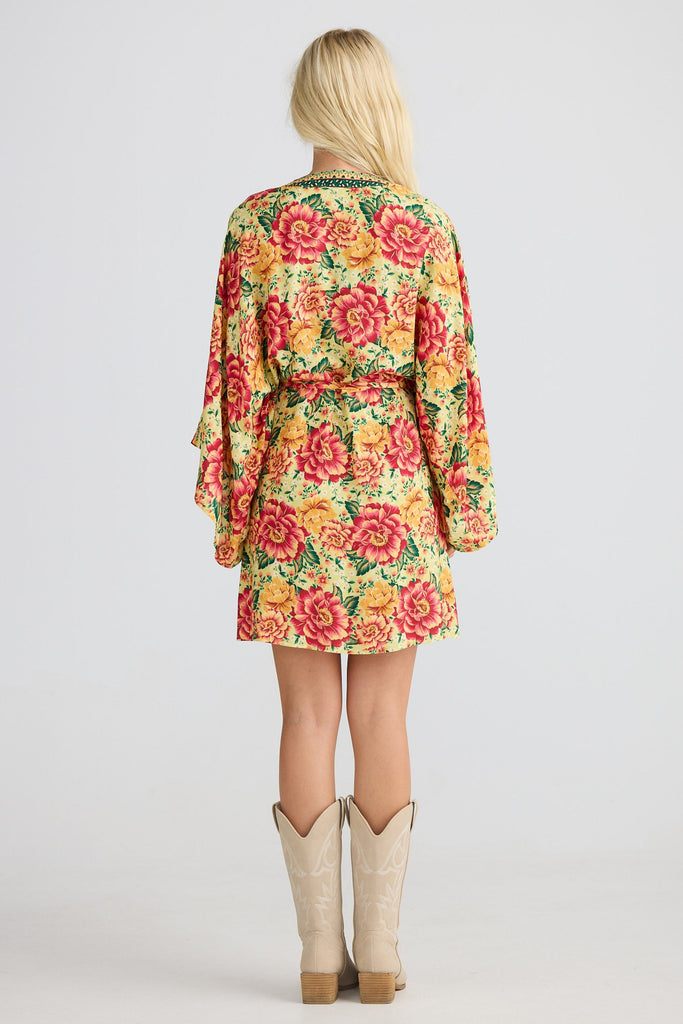 Person wearing a colorful floral dress with a plain background