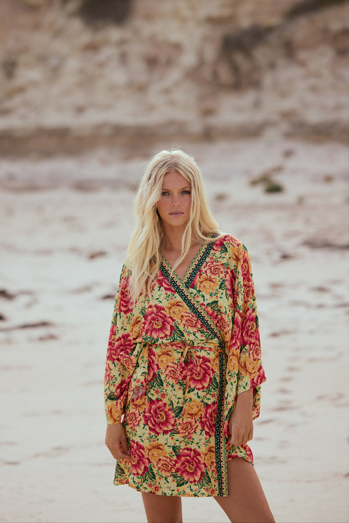 Woman wearing a colorful floral dress on a beach with a blurred background