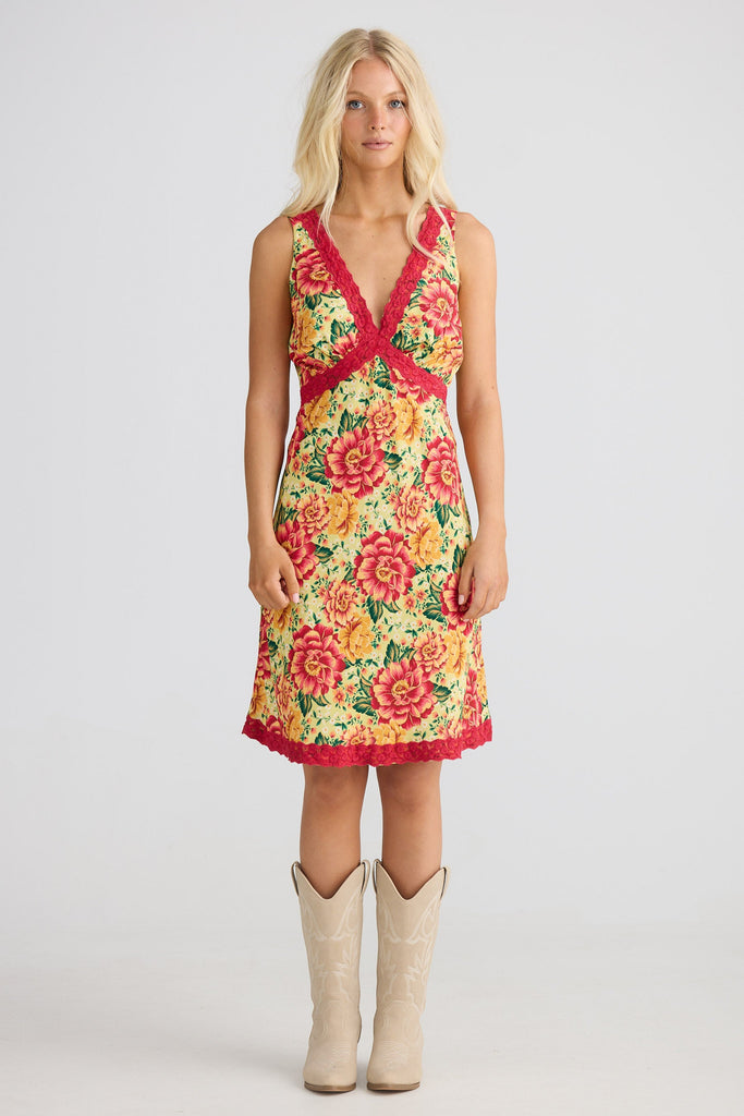 Woman wearing a floral dress with a red waistband on a white background