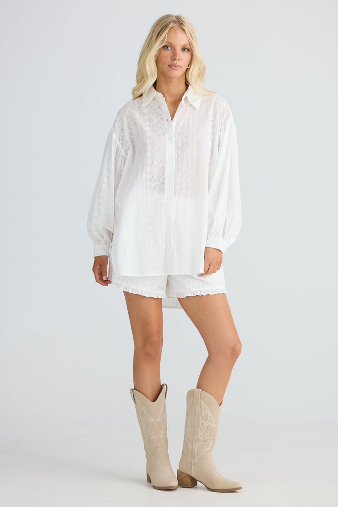 Woman wearing a white shirt and beige boots on a plain background