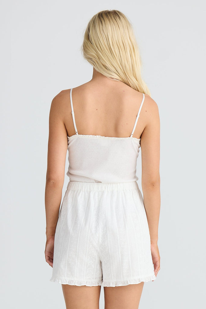 Person wearing a white singlet and shorts on a plain background