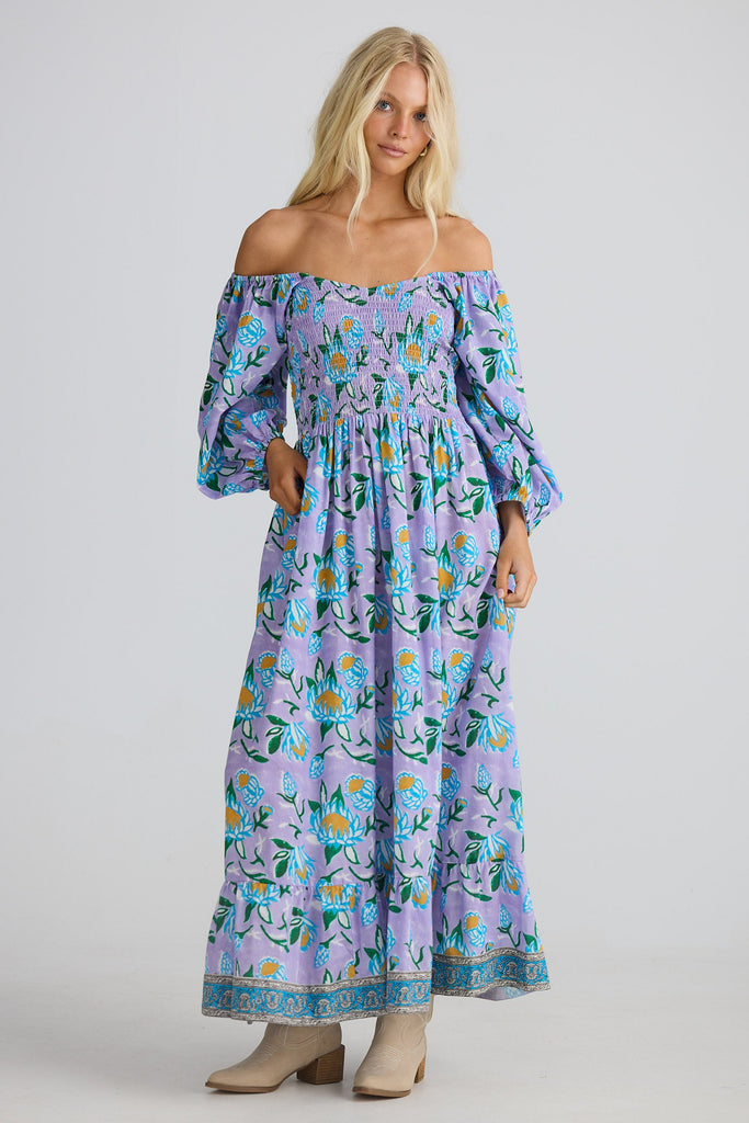 Woman wearing a floral off-shoulder dress on a gray background