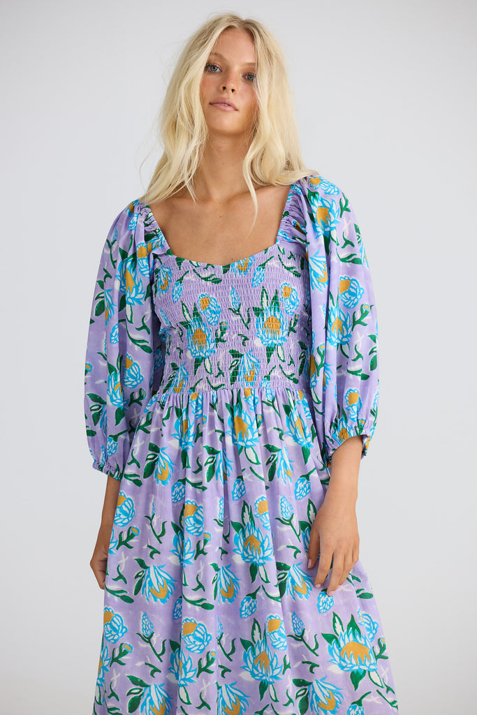 Woman wearing a purple floral dress against a white background