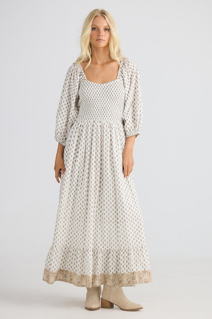 Woman wearing a long, patterned dress on a white background