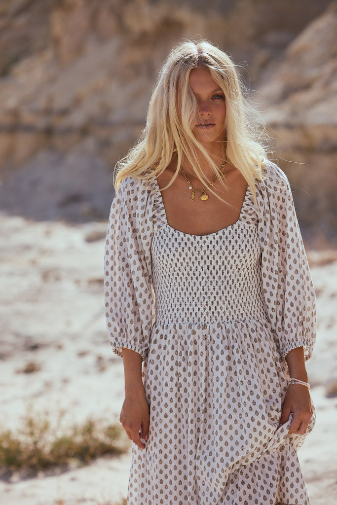 Woman in a patterned dress standing in a desert landscape