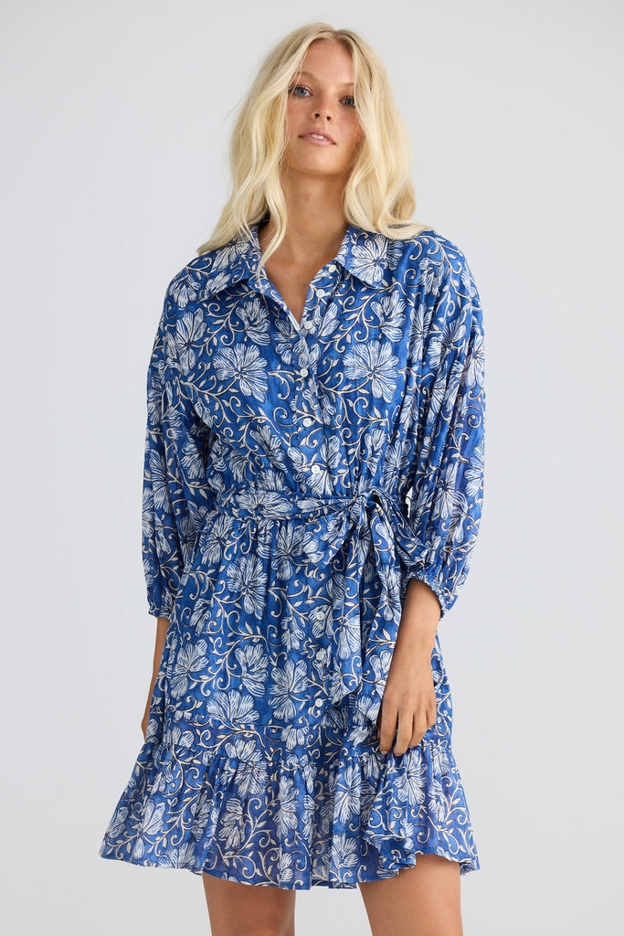 Woman wearing a blue floral dress against a white background