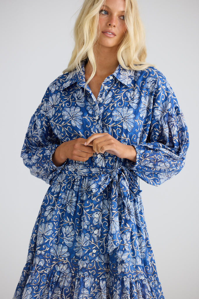 Woman wearing a blue floral dress against a white background
