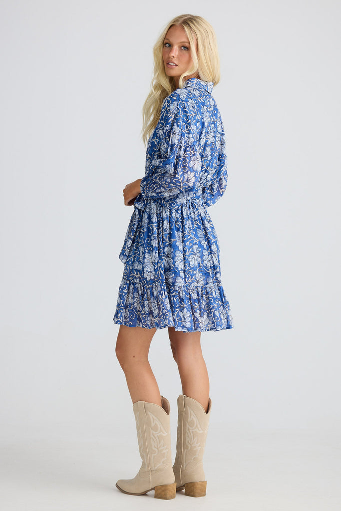 Woman wearing a blue floral dress and beige cowboy boots on a white background