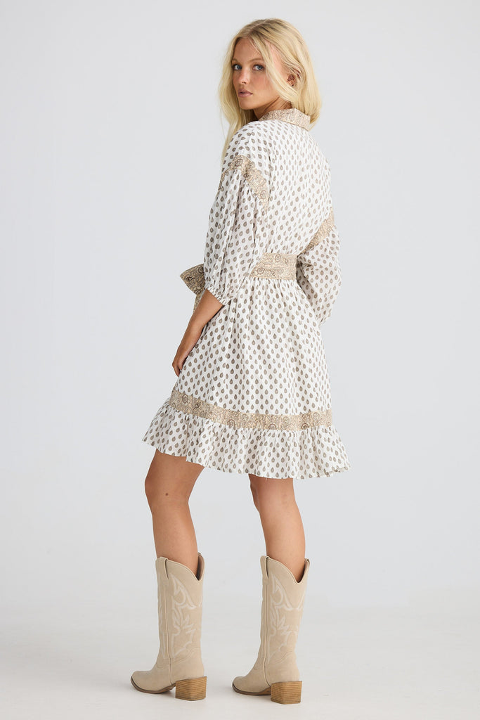 Woman wearing a white dress with patterned and beige cowboy boots on a white background
