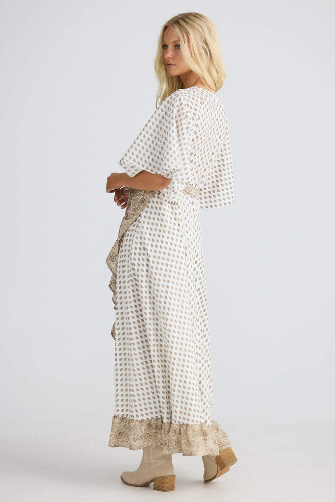 Woman wearing a long, patterned dress with a plain background