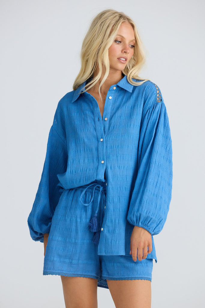 Woman wearing a blue outfit with a matching shirt and shorts on a white background