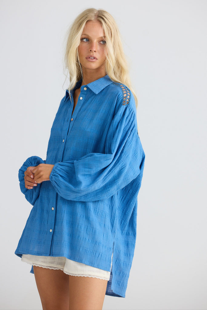 Woman wearing a blue shirt with lace sleeves on a white background