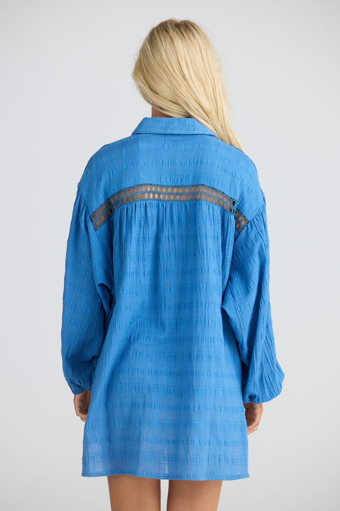 Blue long shirt with lace details on a plain background