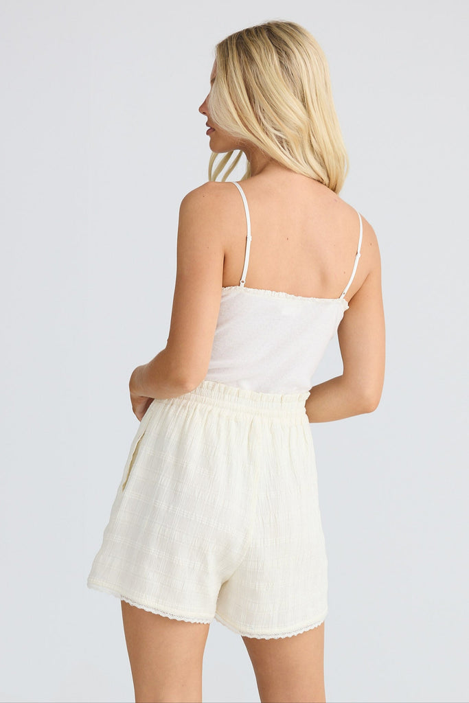 Woman wearing a white top and cream shorts on a white background