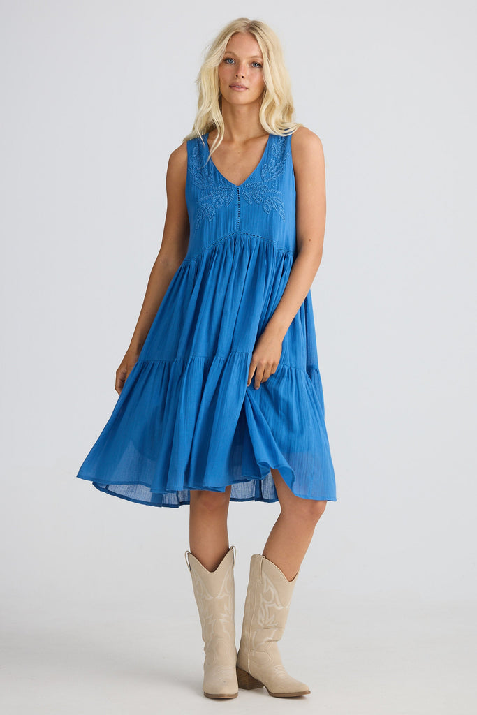 Woman wearing a blue dress and beige boots on a white background