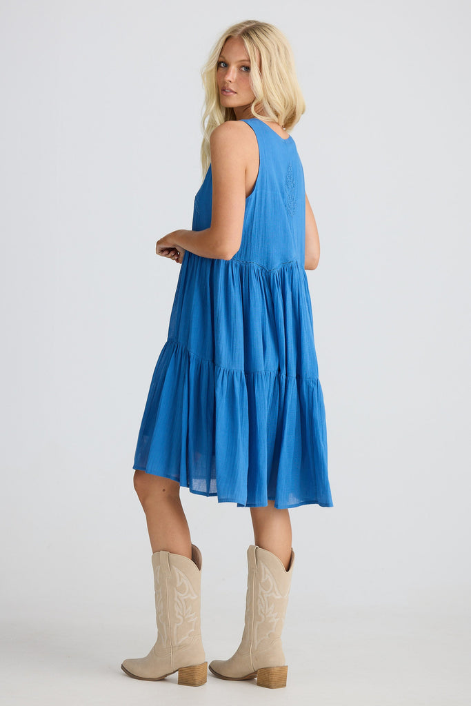 Woman wearing a blue dress with beige boots on a white background