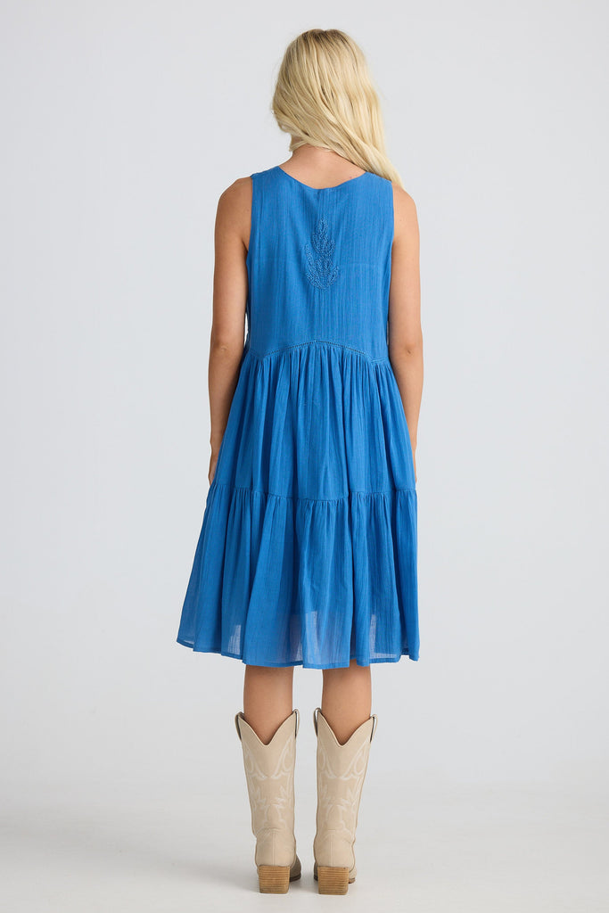 Woman wearing a blue dress with beige boots on a white background