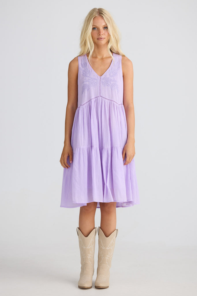 Woman wearing a light purple dress with beige boots on a white background