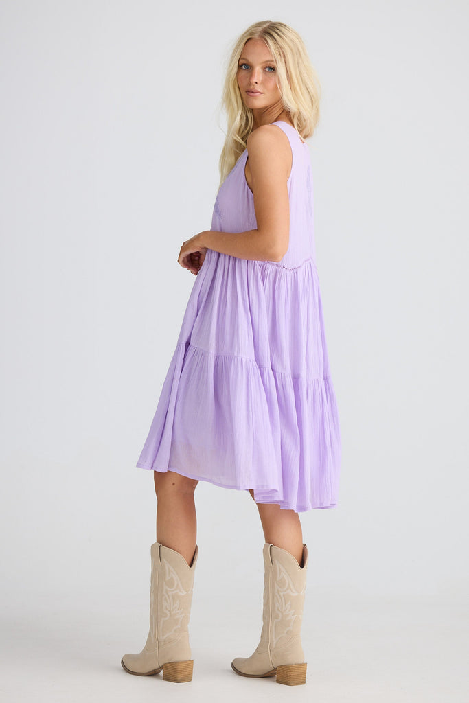 Woman wearing a light purple dress and beige boots on a white background