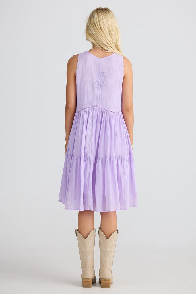 Woman wearing a light purple dress with beige boots on a white background