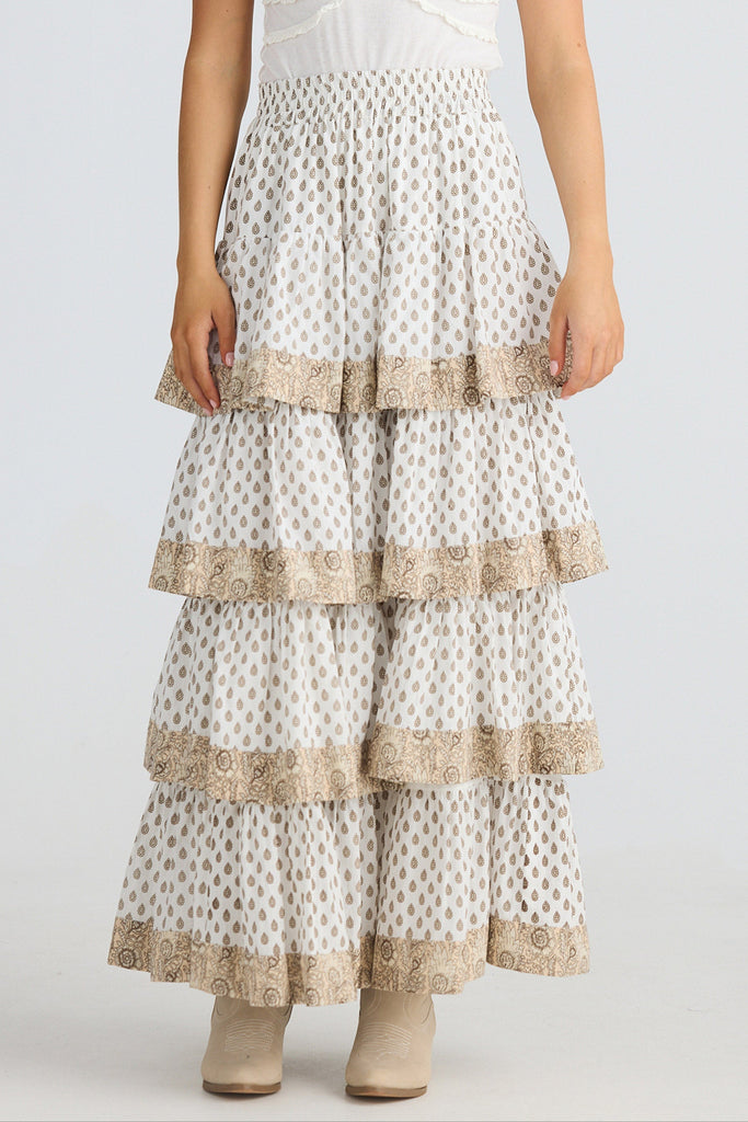 Long, tiered skirt with intricate patterns and trim on a plain background