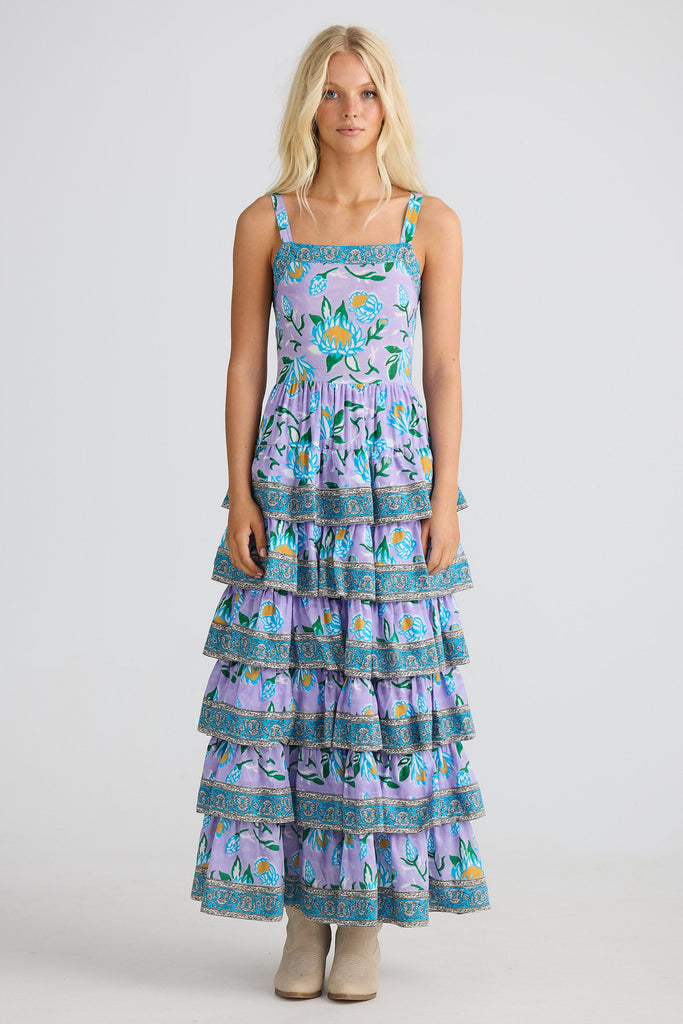 Woman wearing a tiered dress with floral print on a white background