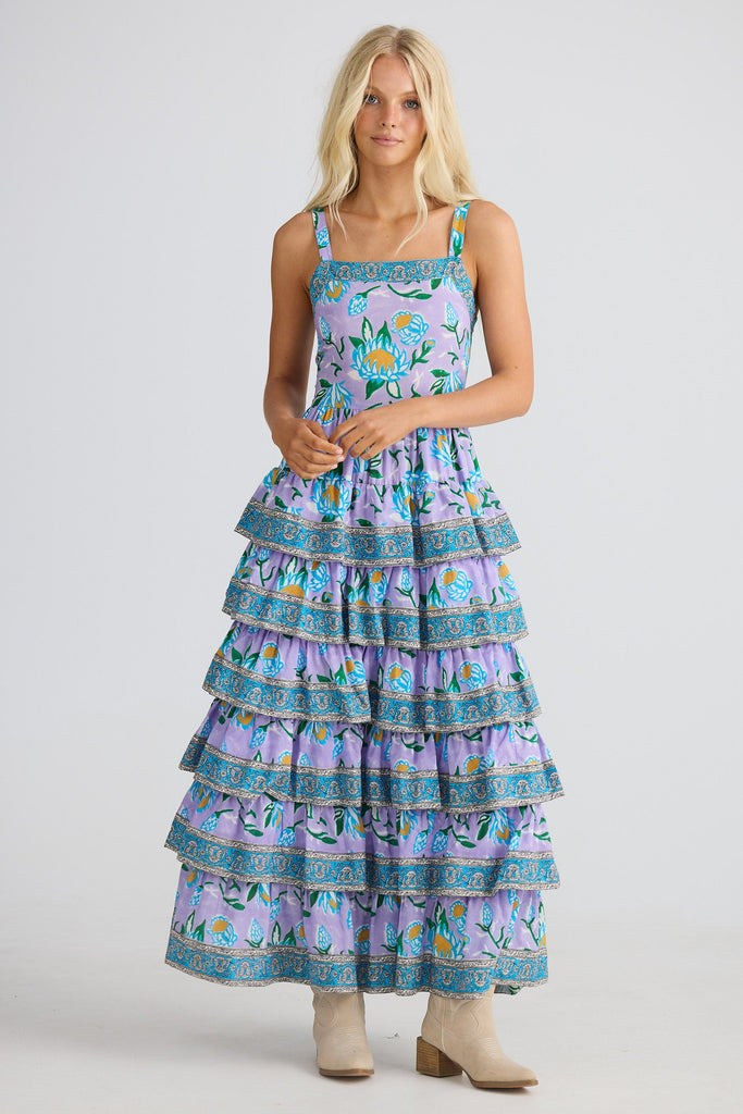 Woman wearing a tiered dress with floral pattern on a plain background