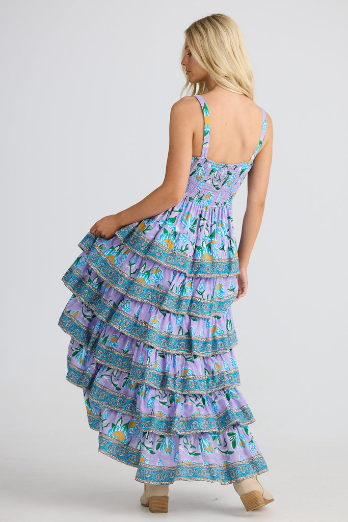 Woman wearing a tiered dress with a colorful pattern on a white background