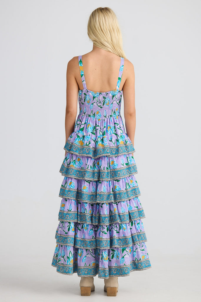 Woman wearing a tiered dress with a floral pattern on a white background