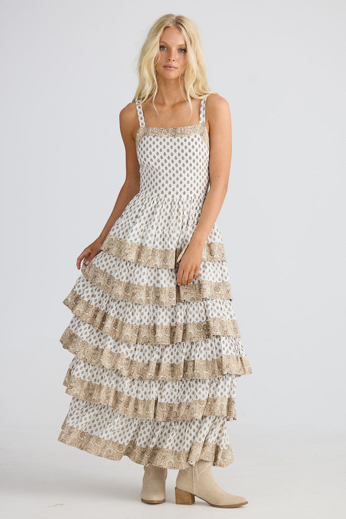 Woman wearing a tiered dress with patterned on a white background