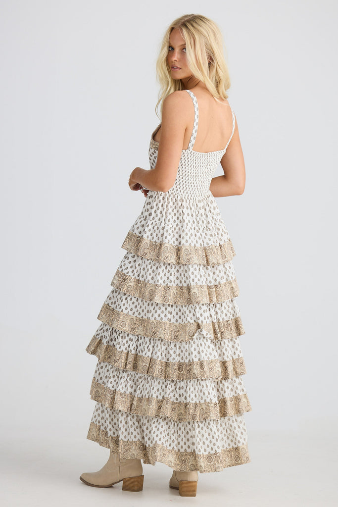 Woman wearing a white dress with ruffled layers on a plain background