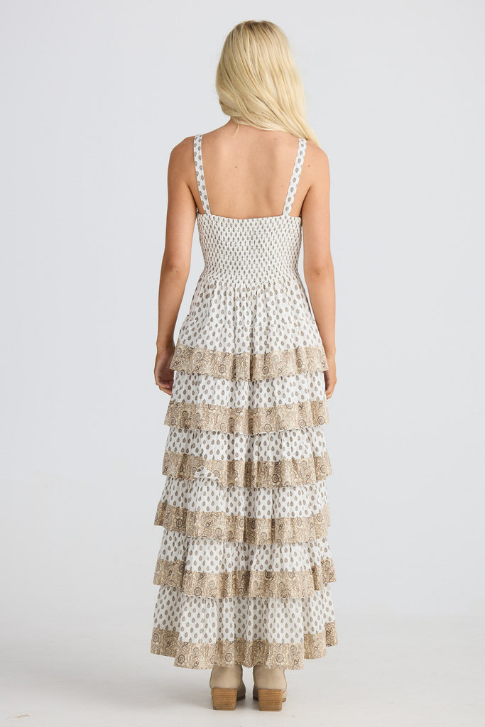 Woman wearing a white and beige patterned dress on a white background