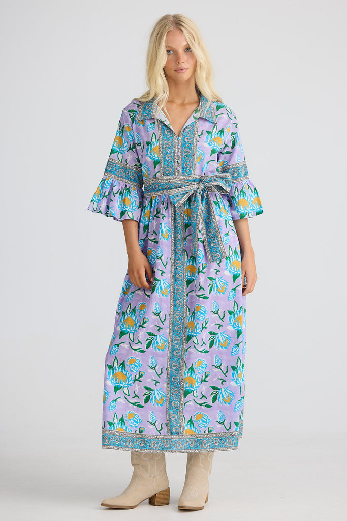 Woman wearing a floral dress with a belt on a white background