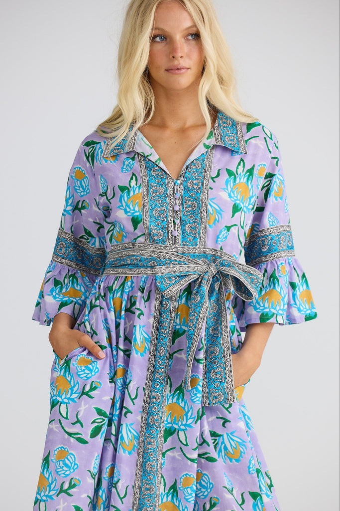 Woman wearing a colorful floral dress with a white background