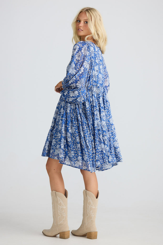 Woman wearing a blue floral dress and beige boots on a white background