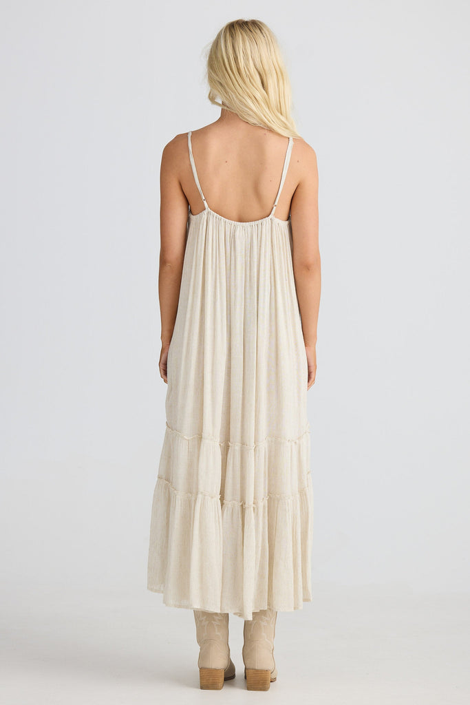 Woman wearing a beige dress with thin straps on a white background