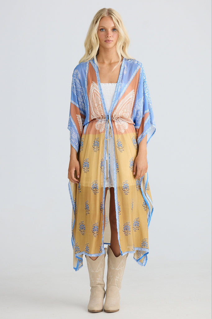 Woman wearing a long, patterned kimono-style garment on a white background