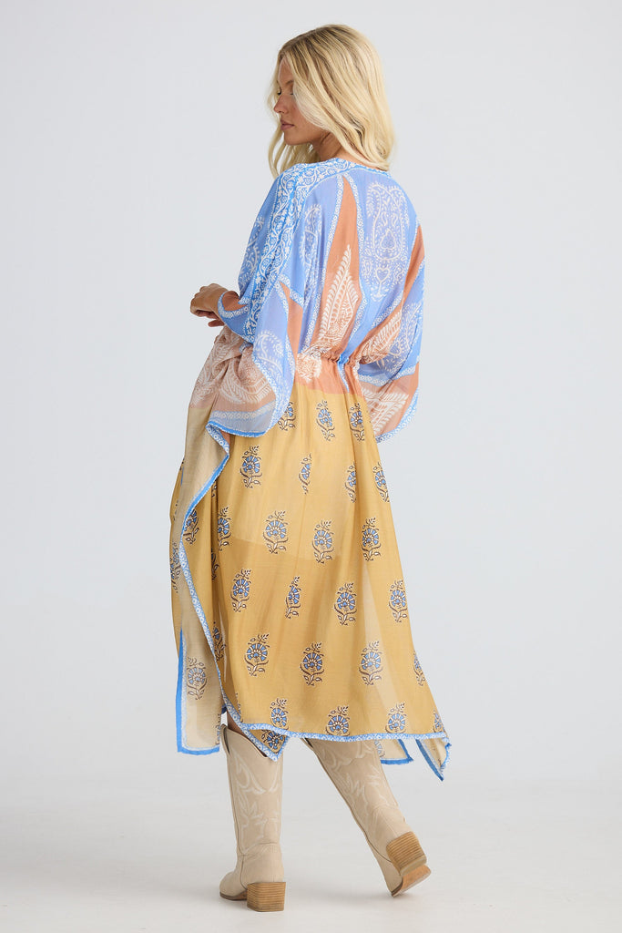 Woman wearing a yellow and blue patterned cape on a white background