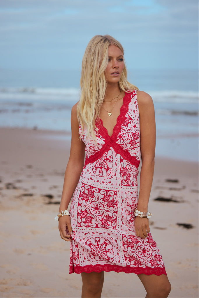 Woman in a red and white dress standing on a beach