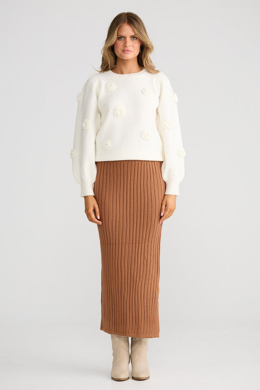 Woman wearing a white sweater and brown ribbed skirt on a white background