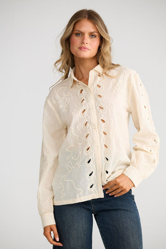 Woman wearing a cream lace-up blouse with a plain background