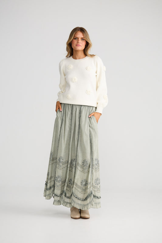 Long, patterned skirt worn by a person on a plain background