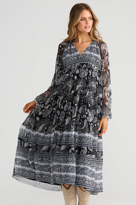 Woman wearing a long, patterned dress on a plain background
