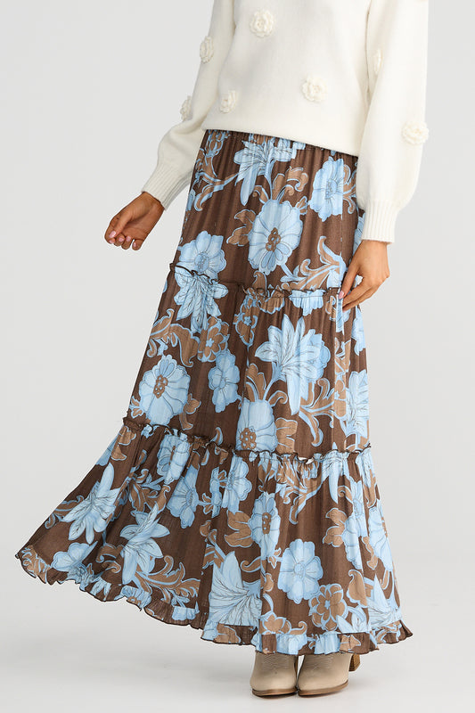 Person wearing a brown floral skirt with blue flowers on a white background